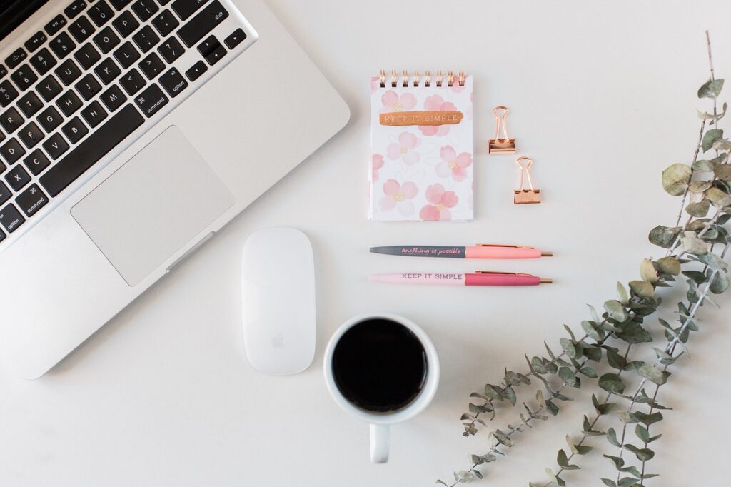 Minimalist workspace with laptop, notepad, pens, and coffee.