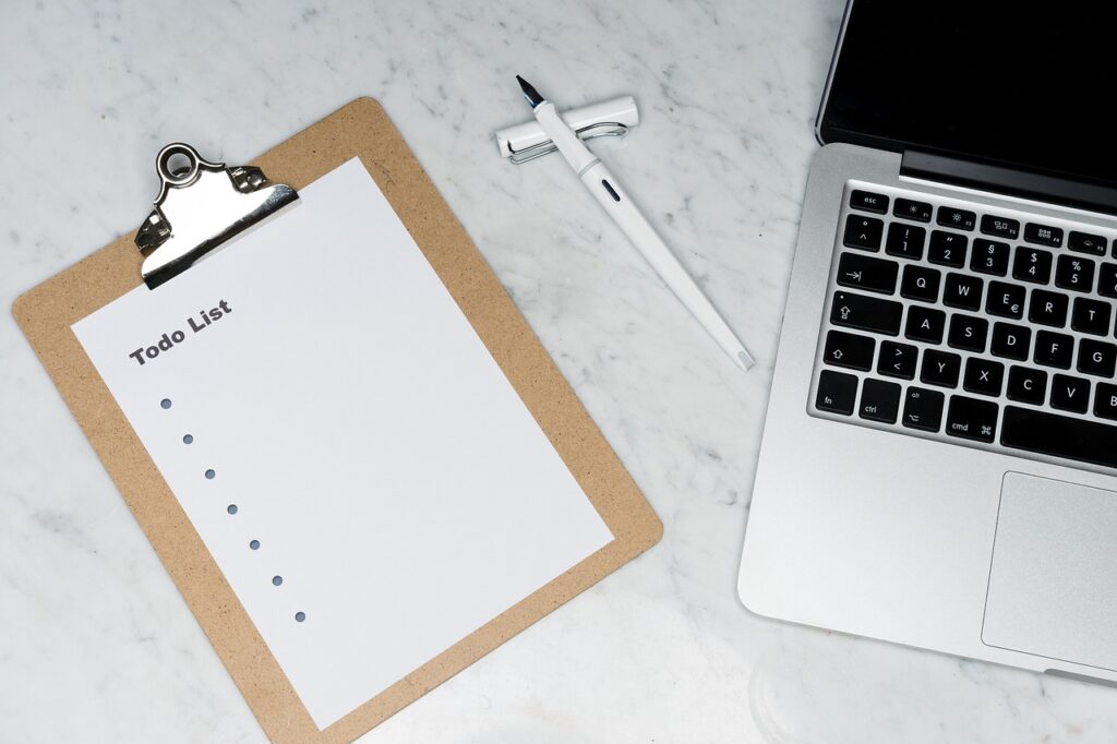 Todo list with laptop and pen on table.