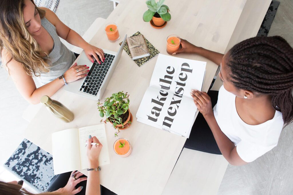 Three women collaborating at a table with laptops