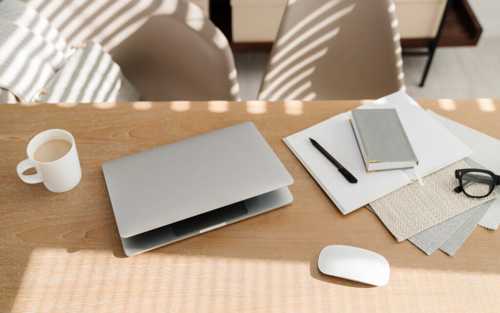 Minimalist desk with laptop, notebook, coffee, glasses.